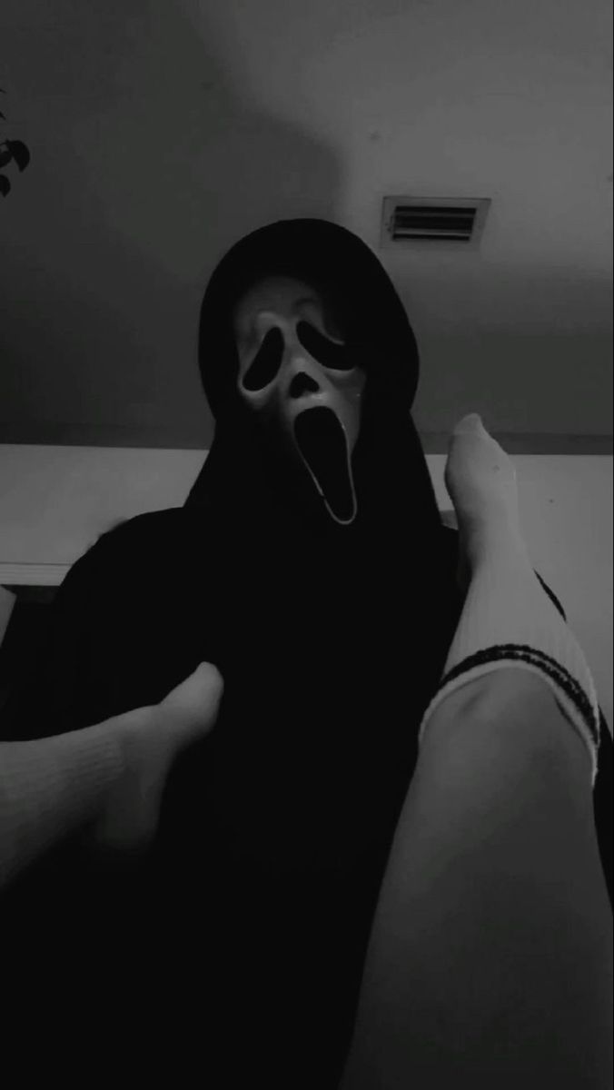 a person in a black hoodie with their mouth open and tongue out while wearing a mask