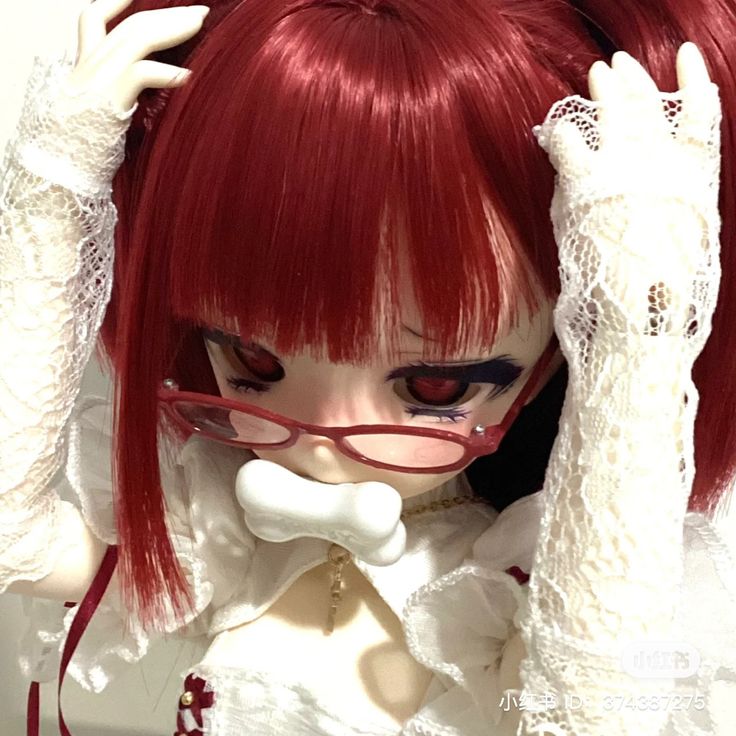 a doll with red hair and glasses holding her head