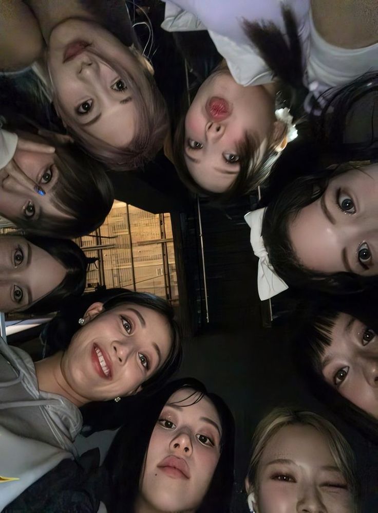 a group of young women standing in a circle looking up at the camera and smiling