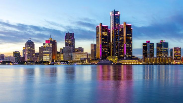 the city skyline is lit up at night, and it's reflecting in the water