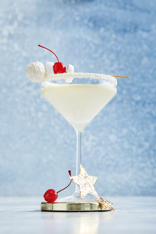 a white cocktail garnished with cherries and sugar