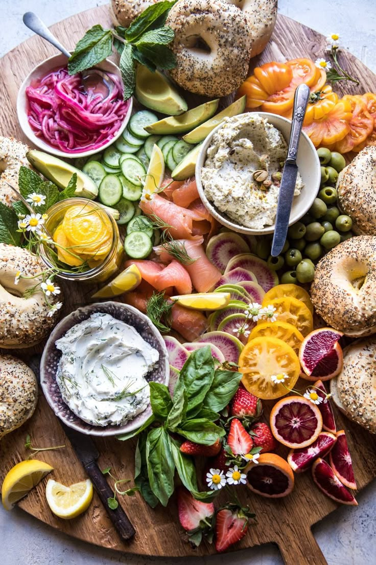 a platter with bagels, vegetables and dips