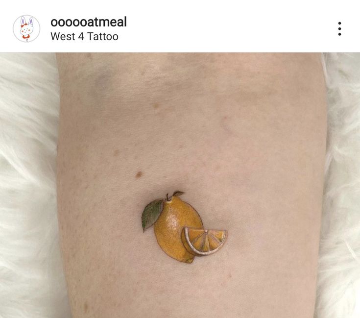 an orange on the side of a woman's leg with a small piece of fruit attached to it