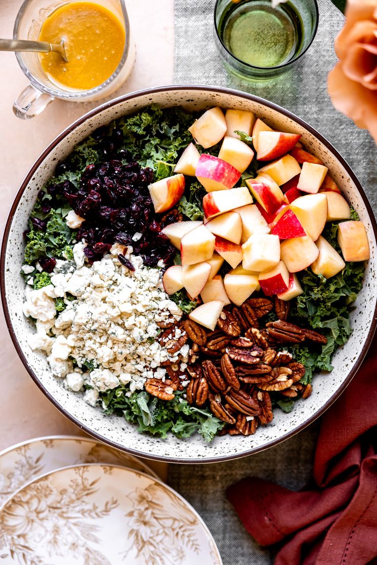 a salad with apples, pecans, blue cheese and cranberries in a bowl