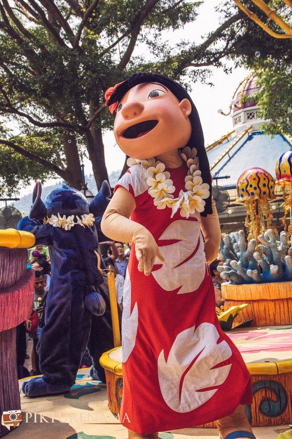 a woman in a red and white dress standing next to a statue of an elephant