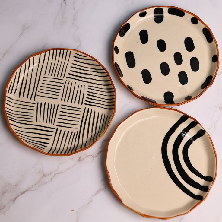 three black and white plates sitting on top of a marble counter