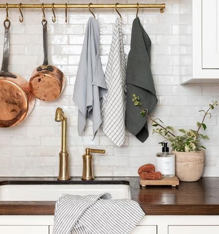 a kitchen counter with pots and pans hanging on the wall next to a sink