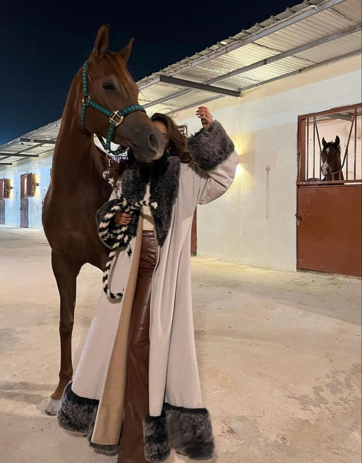 a woman standing next to a brown horse