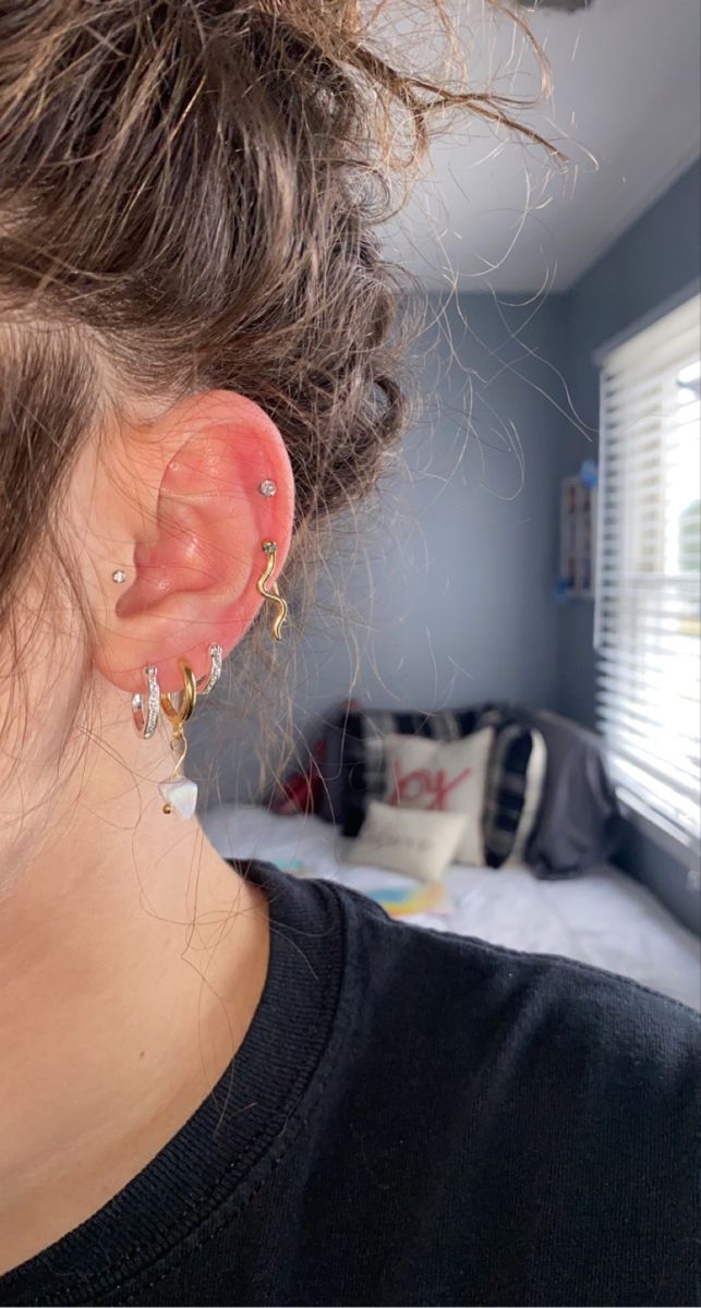 a woman with ear piercings on her ears is looking out the window at something outside