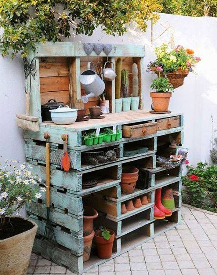 an outdoor potting bench made out of old pallets and wooden crates with gardening tools on top