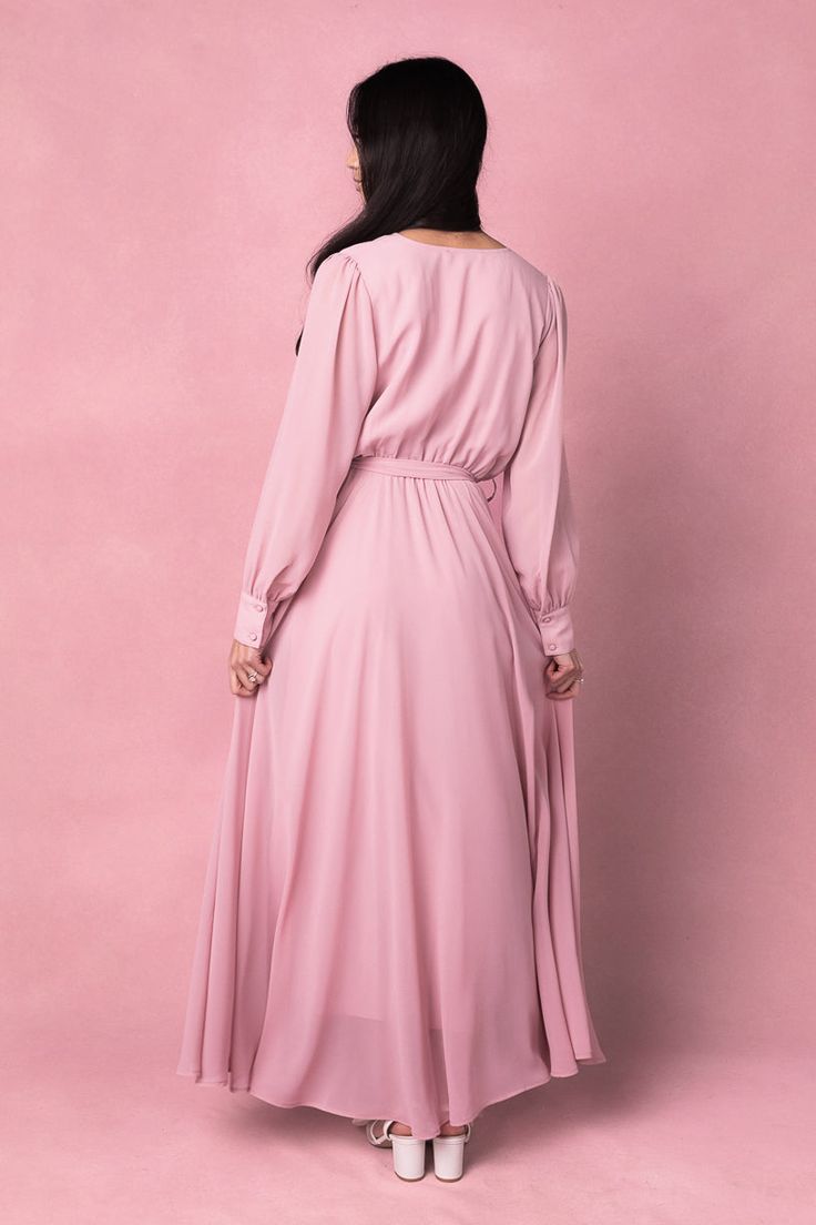 Say hello to the Andie Dress in Blush. Dare we say she's the perfect mother of the bride dress?! She's an amazing blend of style and comfort. This maxi dress features a soft pink base with a flattering faux wrap bodice and elastic waist for a flattering fit. The functional pockets and lined bodice and skirt add practicality, while the fabric's stretch makes it suitable for both maternity and nursing. With a v neckline and long, unlined sleeves, this dress is versatile AND chic. Pink V-neck Midi Dress For Wedding Guest, Pink Flowy Wrap Dress With Surplice Neckline, Modest Bridesmaid Maxi Dress For Spring, Flowy Pink Wrap Dress With Surplice Neckline, Modest Fitted Maxi Dress For Wedding Guest, Elegant Flowy Pink Dresses, Pink Flowy Modest Maxi Dress, Flowy Feminine Maxi Dress For Wedding Guest, Feminine Blush V-neck Maxi Dress