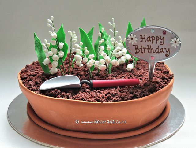 a birthday cake with flowers in a pot and a knife on the plate next to it