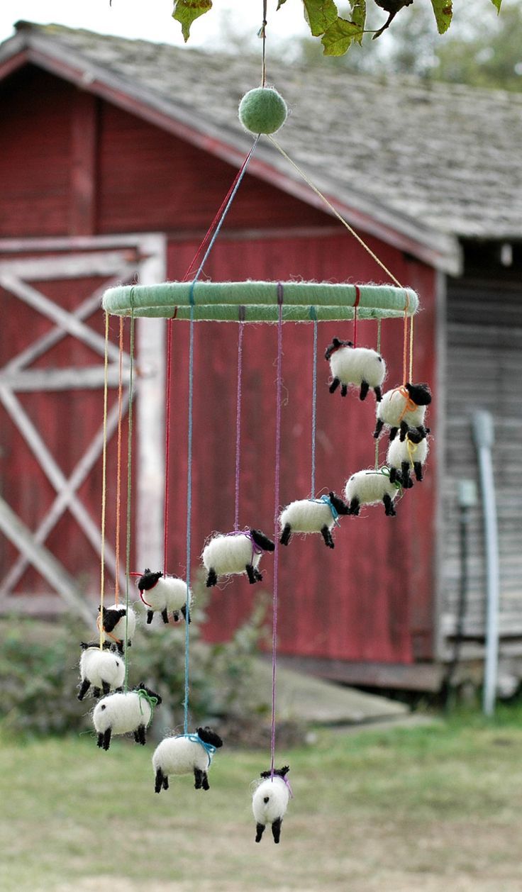 a wind chime hanging from a tree in front of a barn with sheep on it