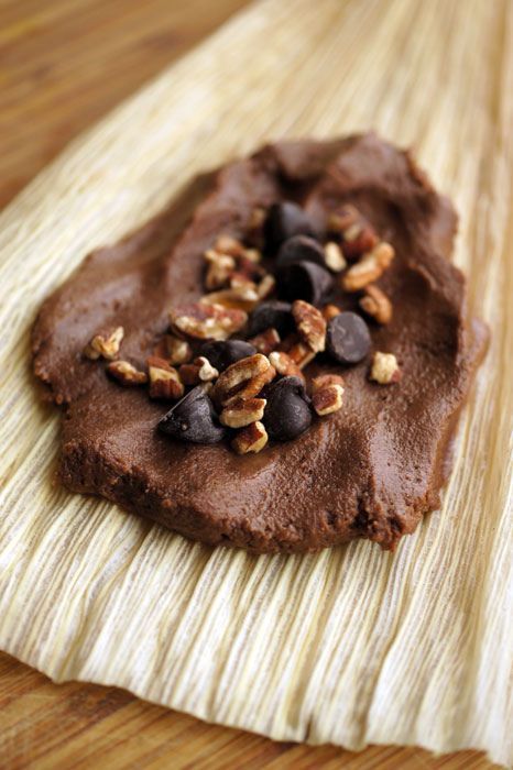 a piece of chocolate cake with nuts on it sitting on top of a wooden table