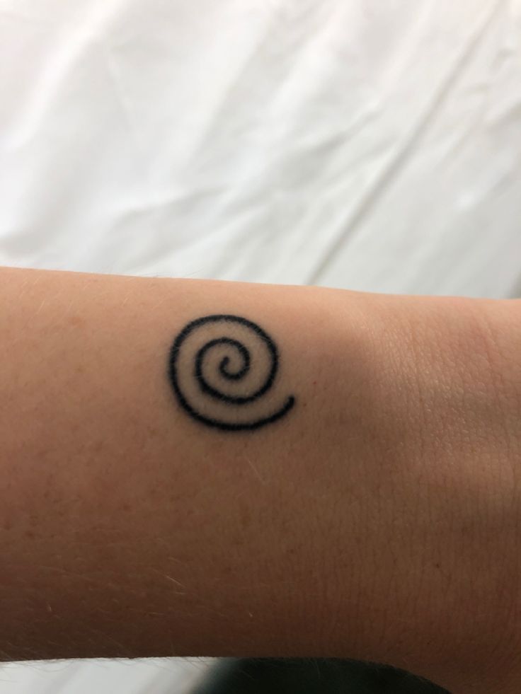 a person with a tattoo on their arm that has a spiral design in the middle