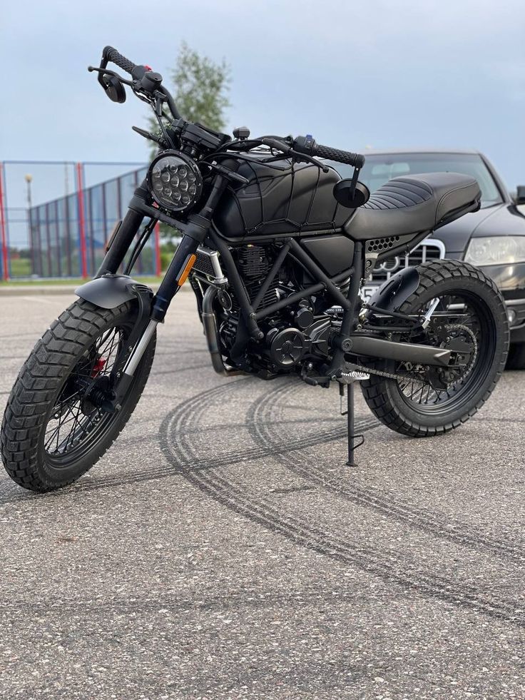 a black motorcycle parked in a parking lot next to a car