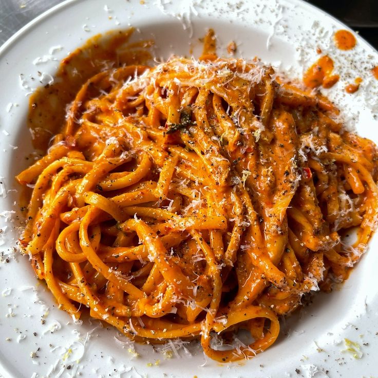 a white plate topped with pasta covered in sauce and parmesan sprinkles