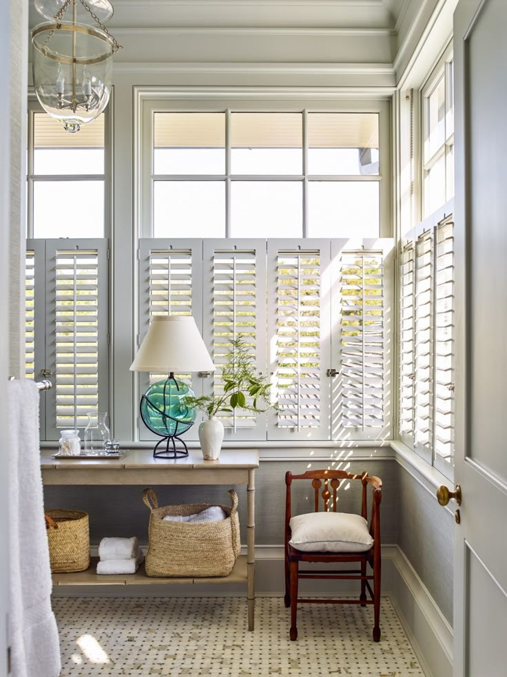 the sun shines through the windows in this white and gray room with two chairs