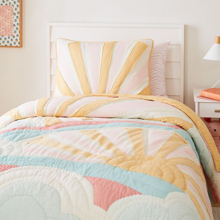 a bed with a colorful comforter and pillows on it in a bedroom next to a lamp