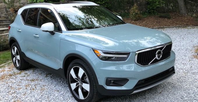 a light blue volvo suv parked on gravel