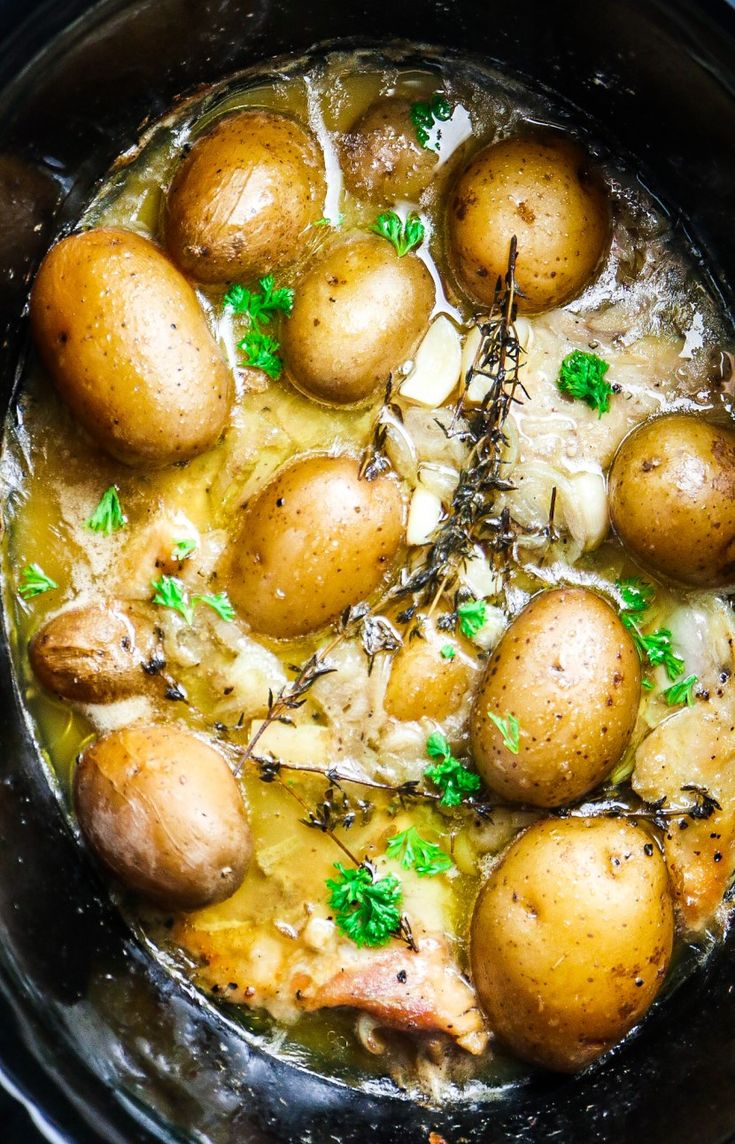 a crock pot filled with chicken and potatoes, garnished with parsley