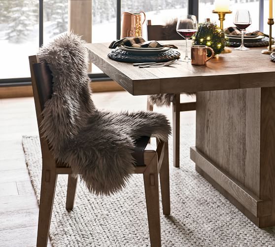 a dining room table with chairs and a christmas tree in the window sill next to it