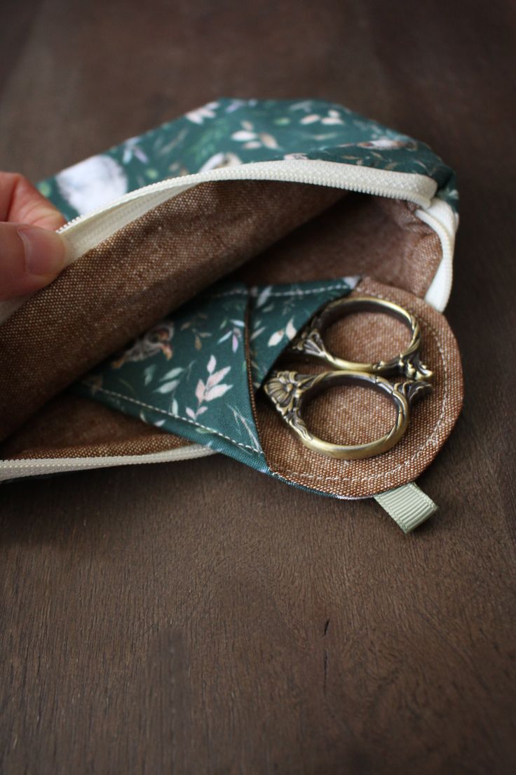 a pair of scissors sitting inside of a small pouch on top of a wooden table