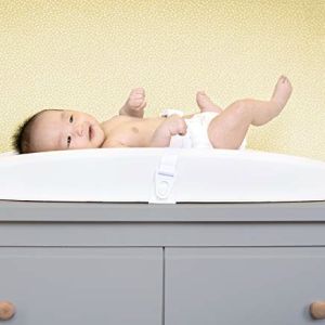 a baby laying on top of a gray dresser next to a wall with yellow walls