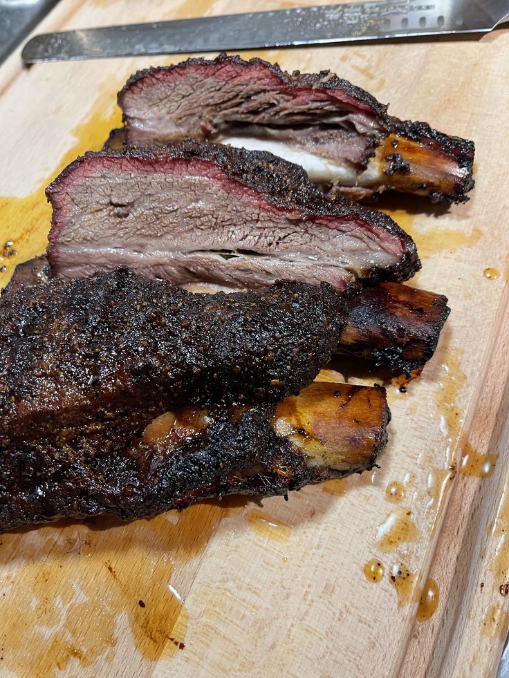 some meat is sitting on a cutting board next to a knife