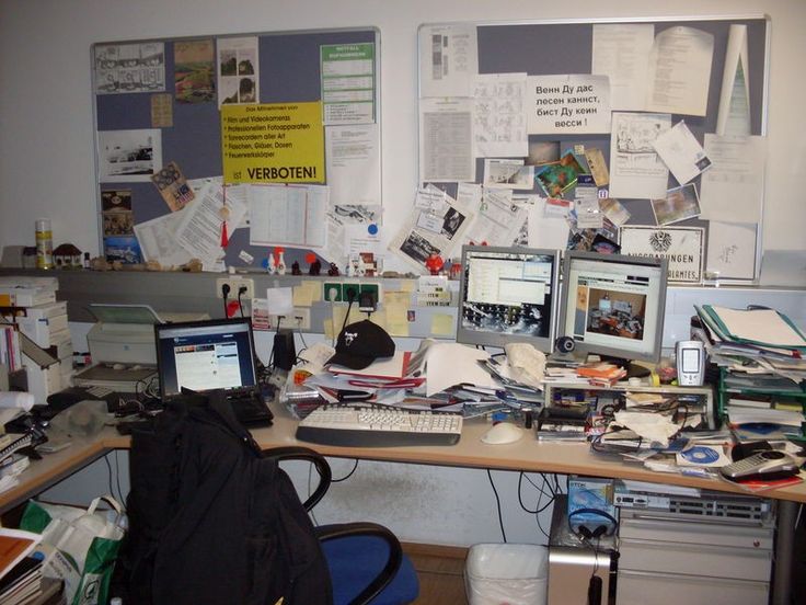 a cluttered desk with several computers and papers on it