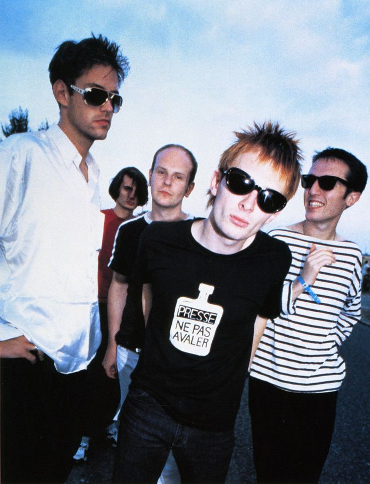 a group of young men standing next to each other in front of a blue sky