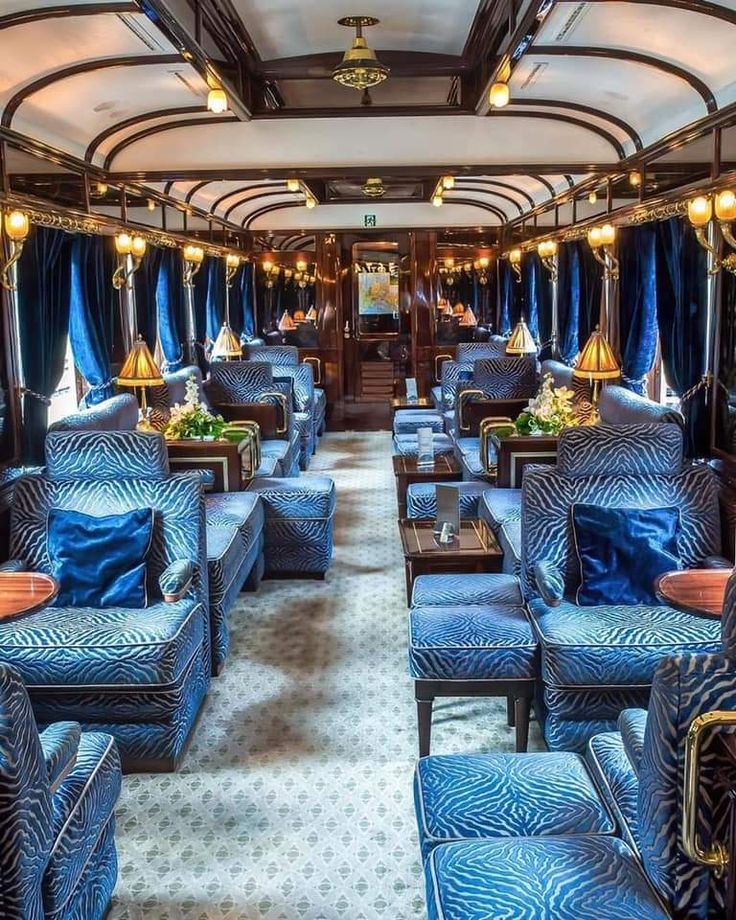 the inside of a train car with blue couches and chairs on each side,