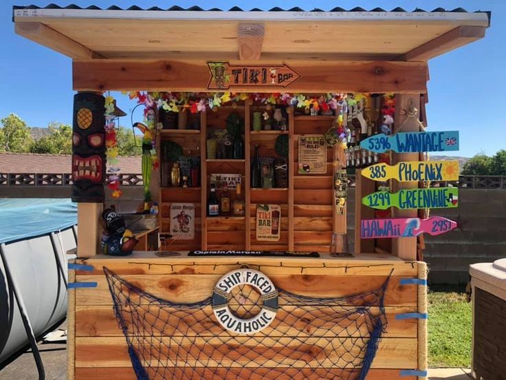 a small wooden bar with many signs on the front and back wall, along with a boat in the background