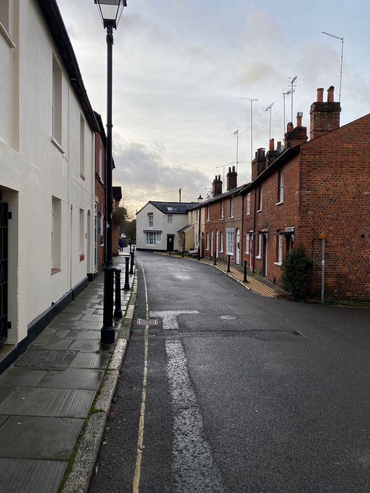 an empty street lined with brick buildings next to a light pole and lampposts