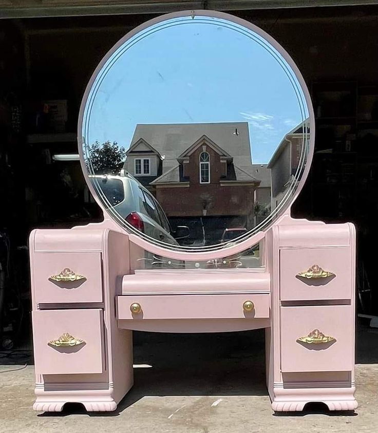 a pink vanity table with a mirror on it and a car parked in front of the house