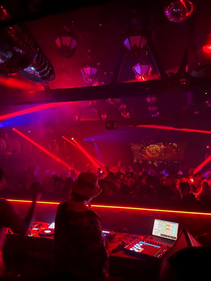 a dj mixing in front of a crowd at a nightclub with red and blue lights