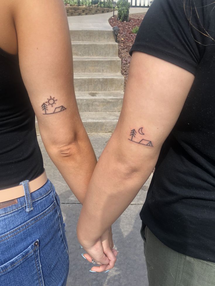 two people holding hands with small tattoos on their arms and palm trees in the background