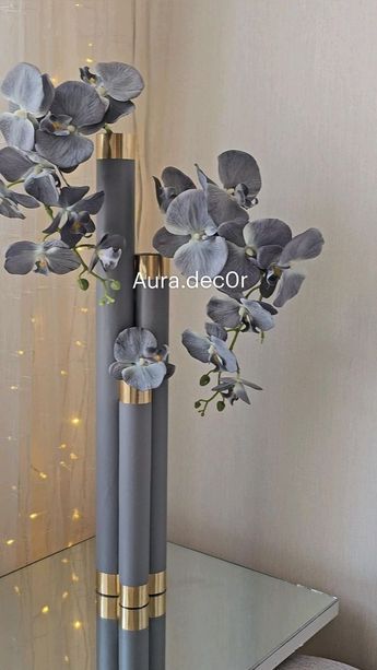 two vases with flowers in them sitting on a table next to a mirror and lights