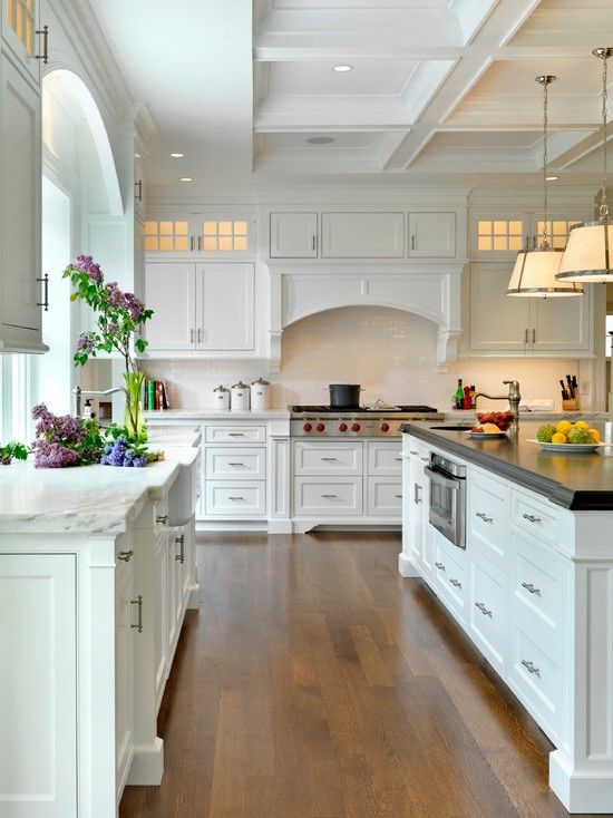 a large kitchen with white cabinets and black counter tops, along with an island in the middle