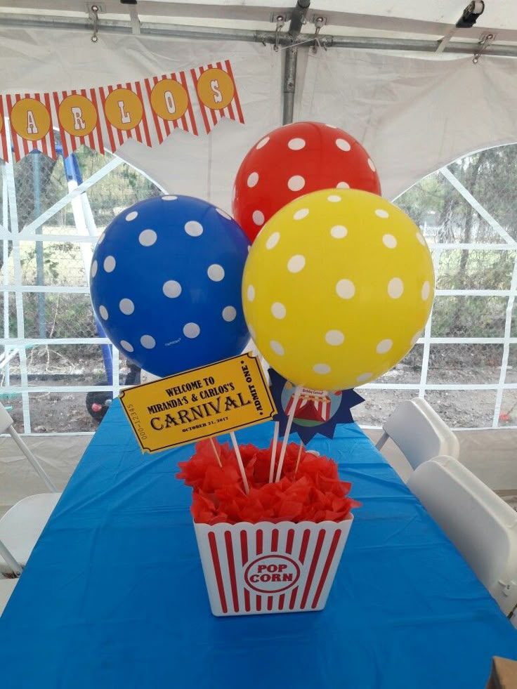 some balloons that are sitting in a cup on a blue table cloth with red and yellow streamers