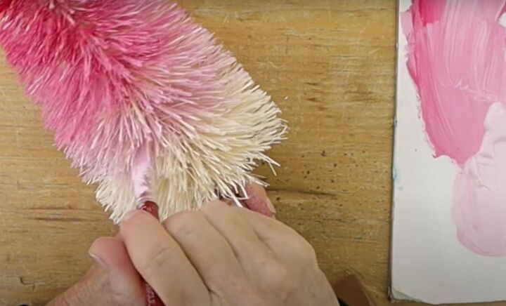 someone is painting pink and white feathers on a piece of wood