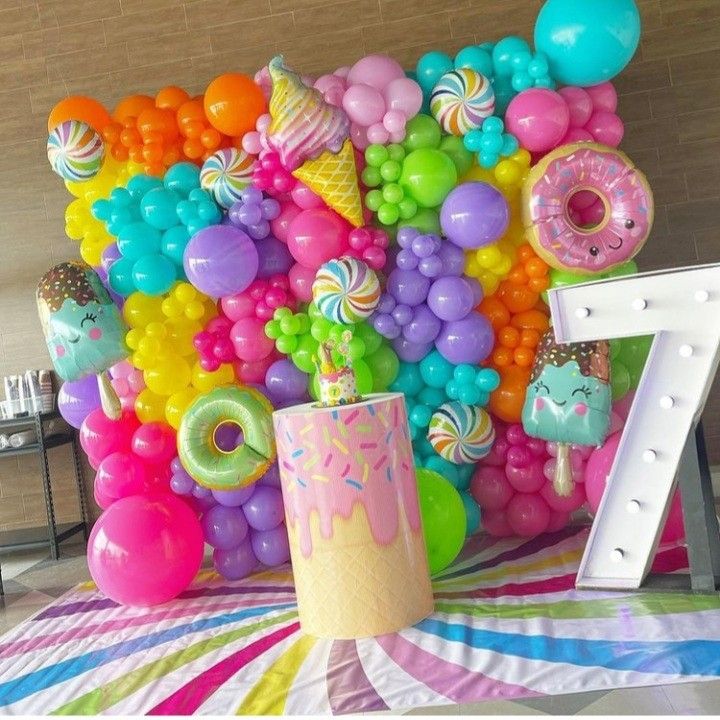 a table topped with balloons and donuts next to a large number seven balloon wall