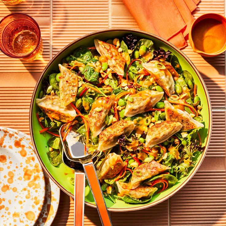 a green plate topped with meat and vegetables next to glasses of tea on a table