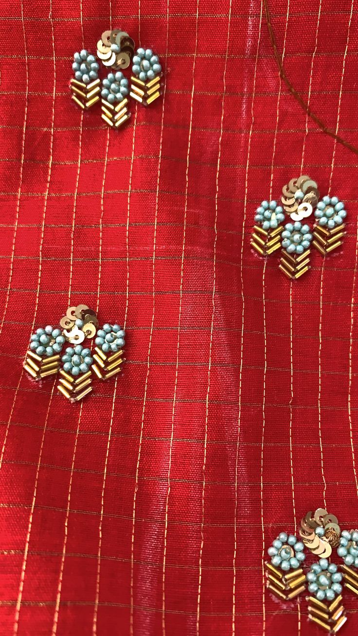 three pieces of broochies sitting on top of a red piece of cloth with gold and blue pins