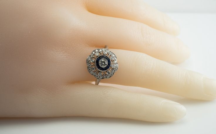 Art Deco Ring, Genuine Diamond Ring, Genuine Sapphire Ring, September Birthstone, Vintage Ring, 14K White Gold Ring, Engagement Ring, Wedding Ring, Elegant Ring. This pretty vintage estate ring is crafted in solid 14K White Gold (carefully tested and guaranteed). The center round brilliant cut diamond is .20 carat. 8 surrounding diamonds total .24 carat. And 24 small diamonds total .24 carat. The total diamond weight is .68 carats. They range from VS2 to SI2 clarity and H color. 14 French cut ab Art Deco Halo Ring With Round Cut, Victorian Style Diamond White Round Cut Diamond Ring, Victorian Diamond Ring With Round Cut, Antique Platinum Cluster Ring, Art Deco Diamond Wedding Ring With Halo Setting, Art Deco Diamond Halo Ring With Round Cut, Victorian Single Cut Diamond Ring, Antique Round Diamond Ring With Single Cut Diamonds, Victorian 14k Gold Round Cut Diamond Ring