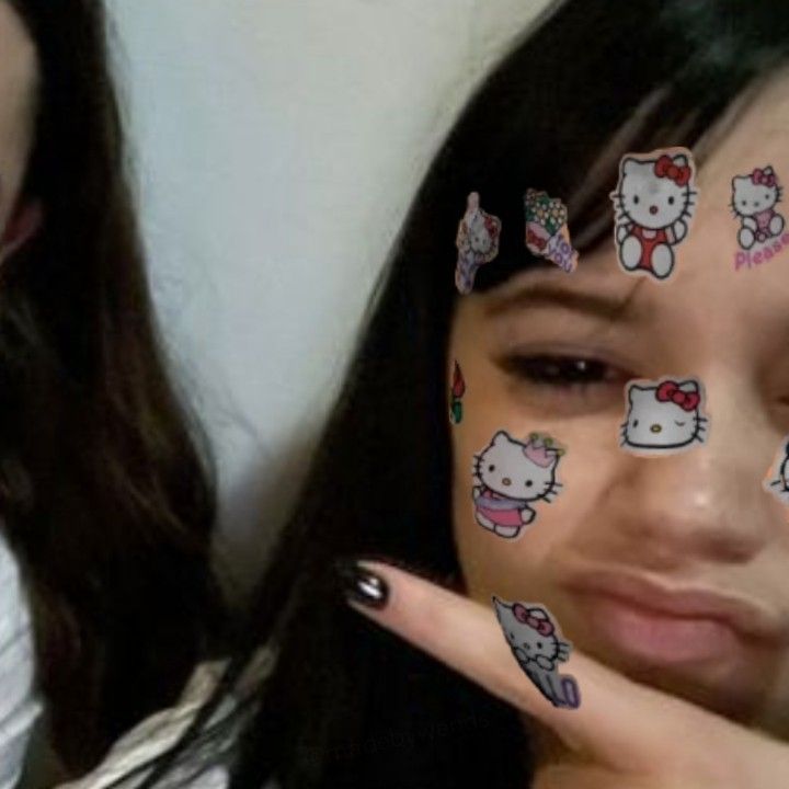 two girls with hello kitty nail decals on their face and one girl has her fingers painted