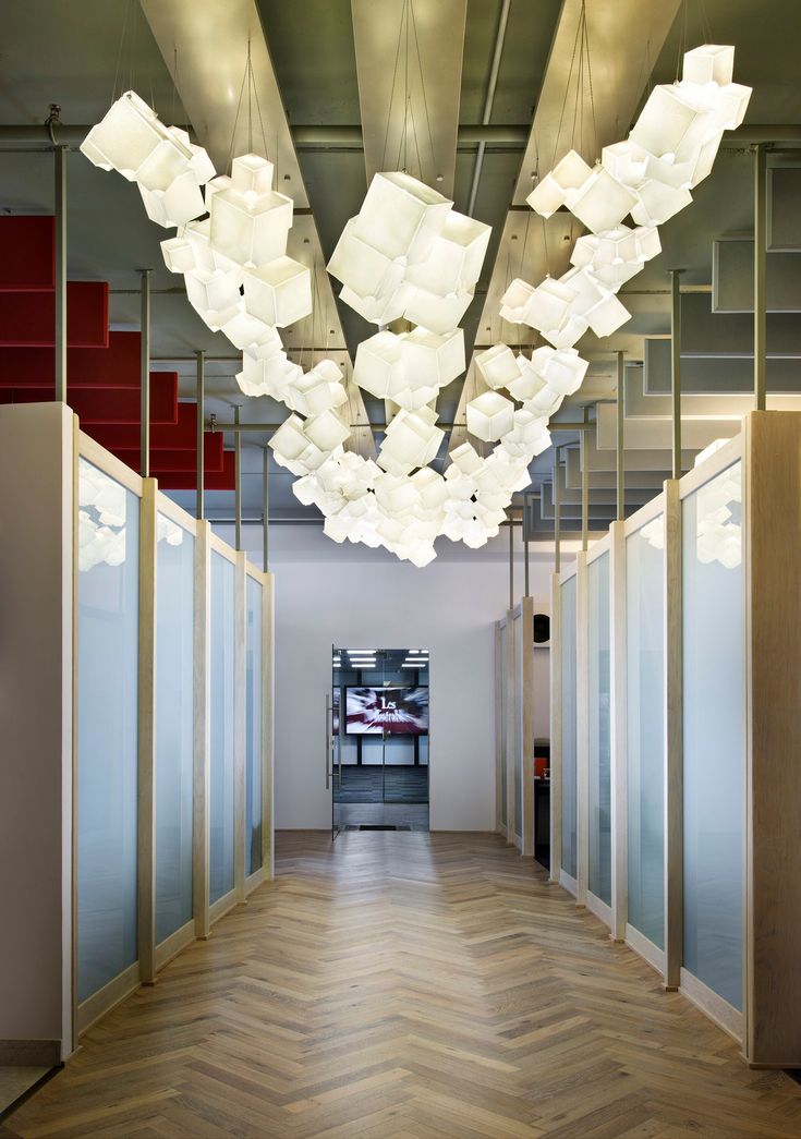 a long hallway with many lights hanging from the ceiling and wooden floors on both sides