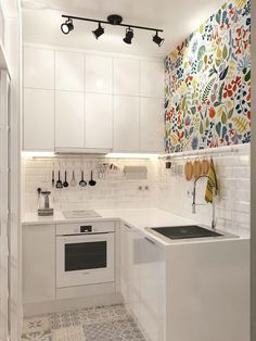 a kitchen with white cabinets and colorful wallpaper