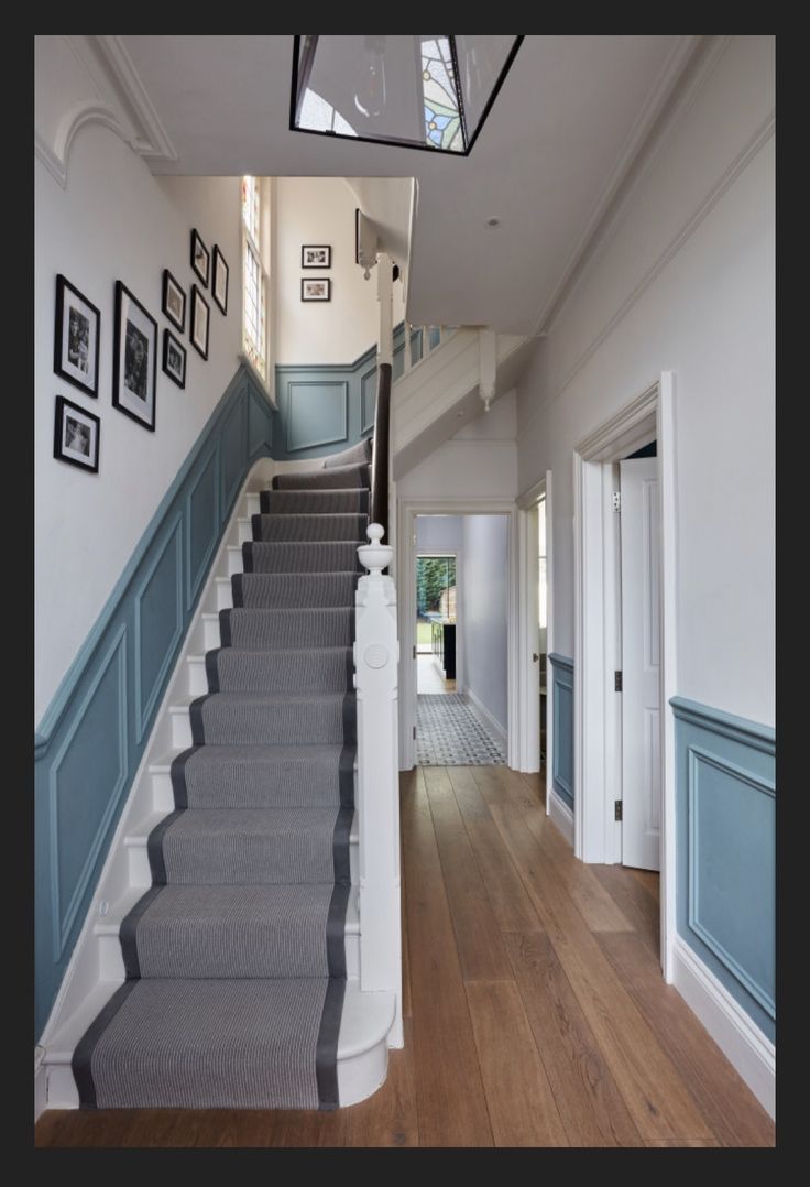 the stairs are painted blue and white with pictures on the wall above them, along with wood flooring