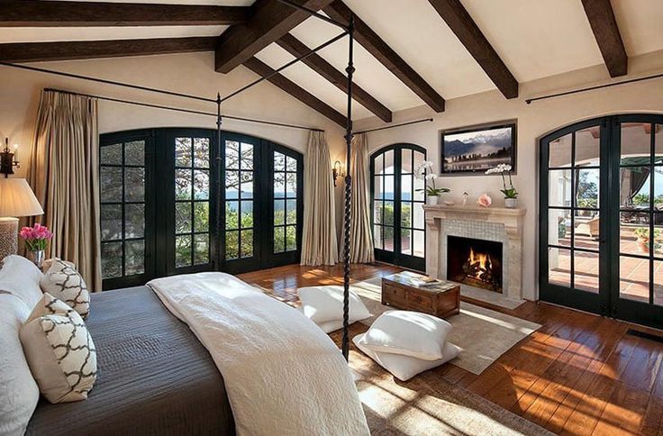 a bedroom with a fireplace, bed and french doors leading to the outside patio area